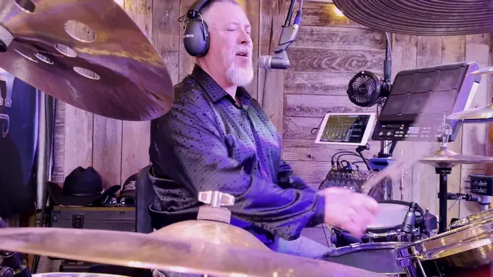 Drummer in headphones behind the kit